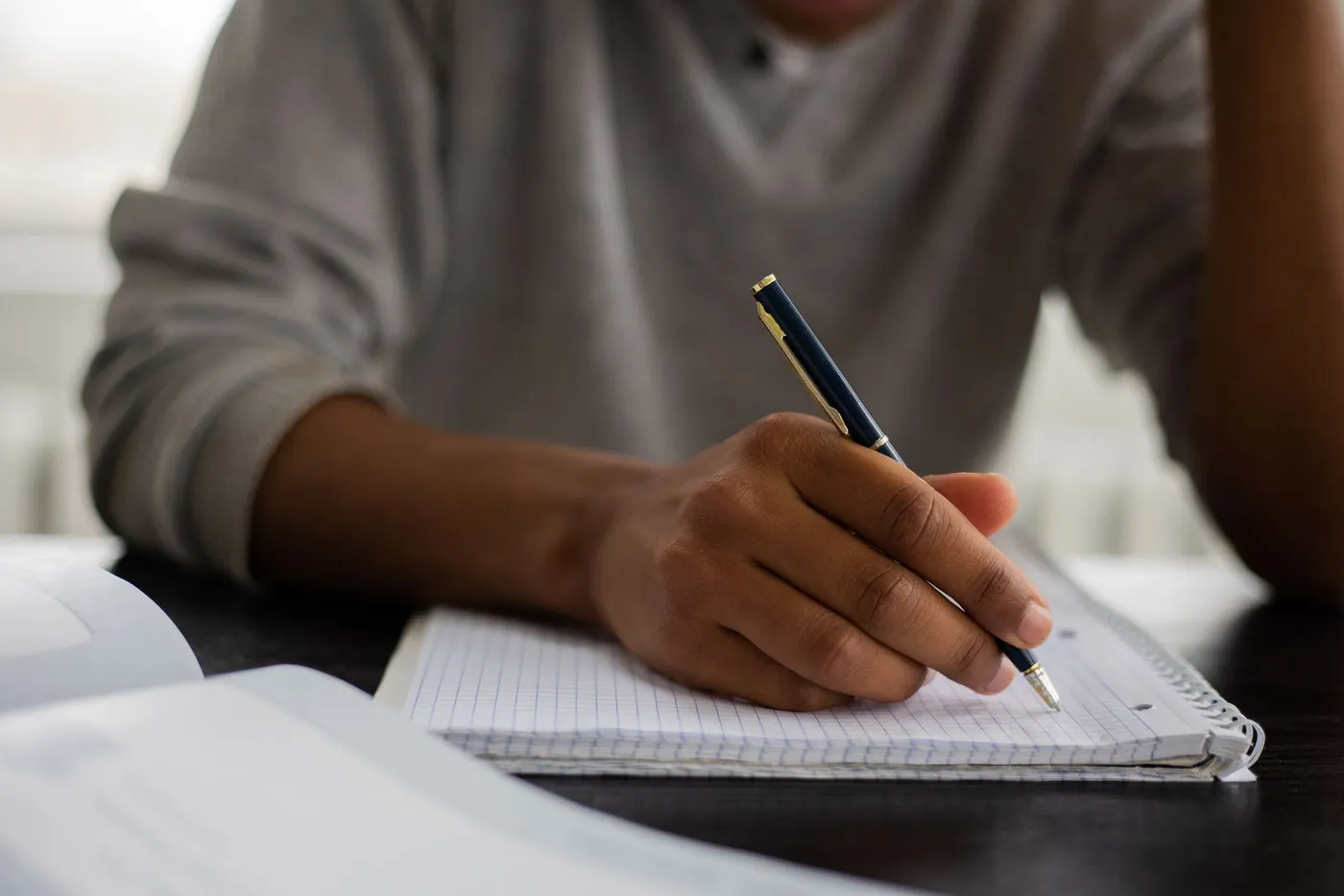 Manos de un adulto escribiendo con esfero en un cuaderno cuadriculado